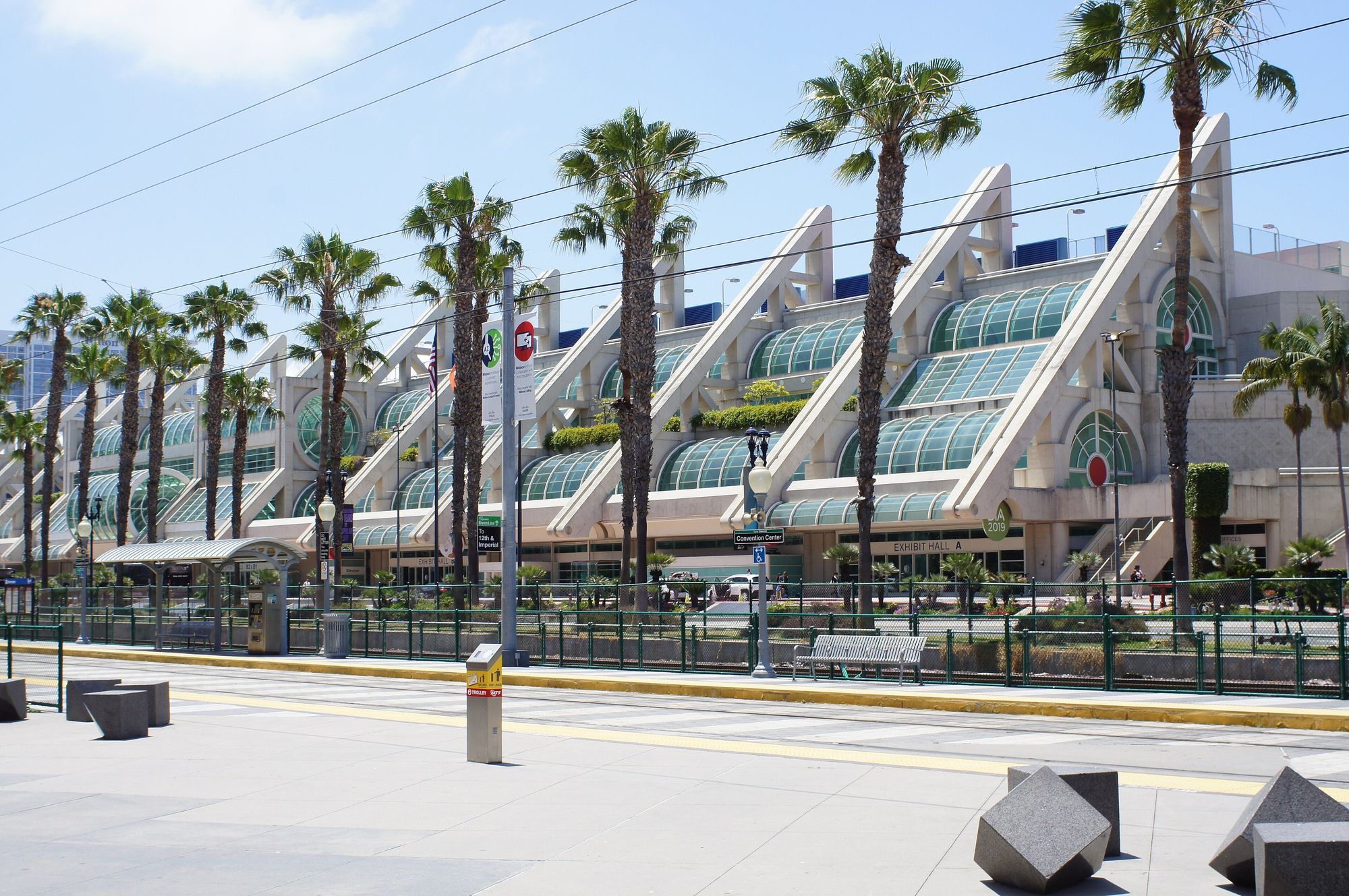 The San Diego Convention Center in downtown San Diego: white sail-shaped facade with glass atriums behind a row of palm trees